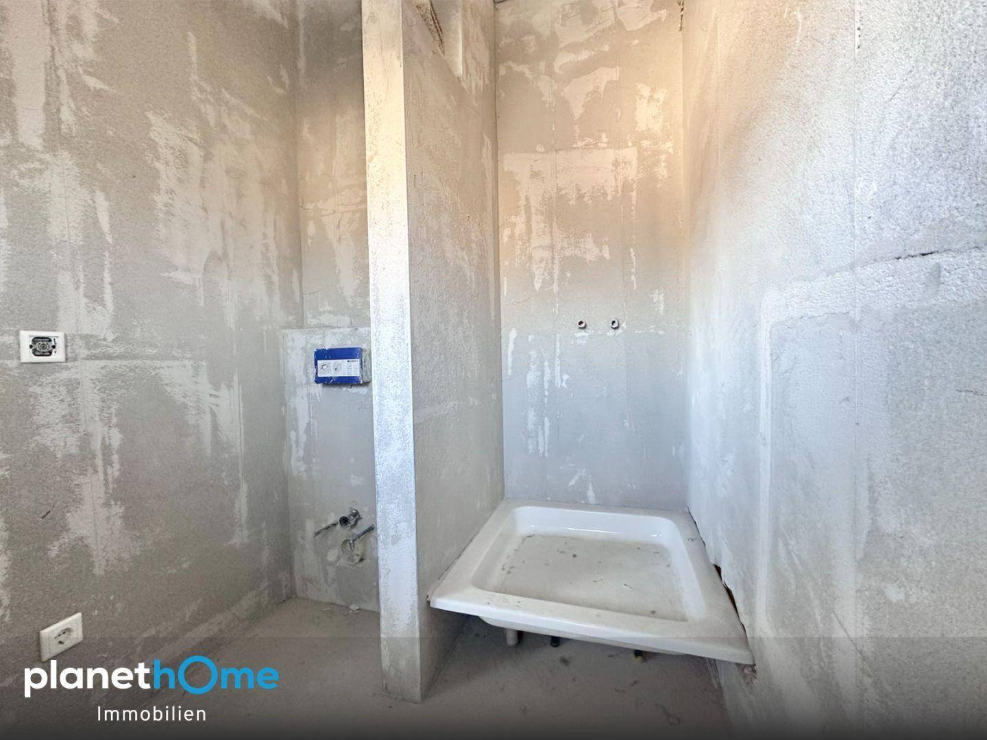 Badezimmer im Rohbau mit vorbereiteter Dusche und Toiletteninstallationen, bereit für den Ausbau.