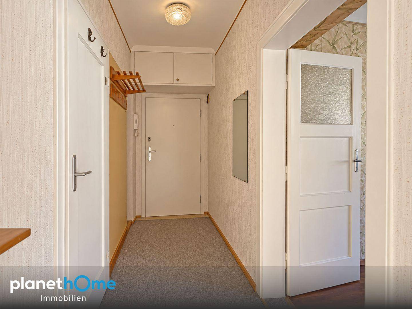 Eingangsbereich mit Teppichboden, Garderobe und Zugang zu verschiedenen Zimmern.