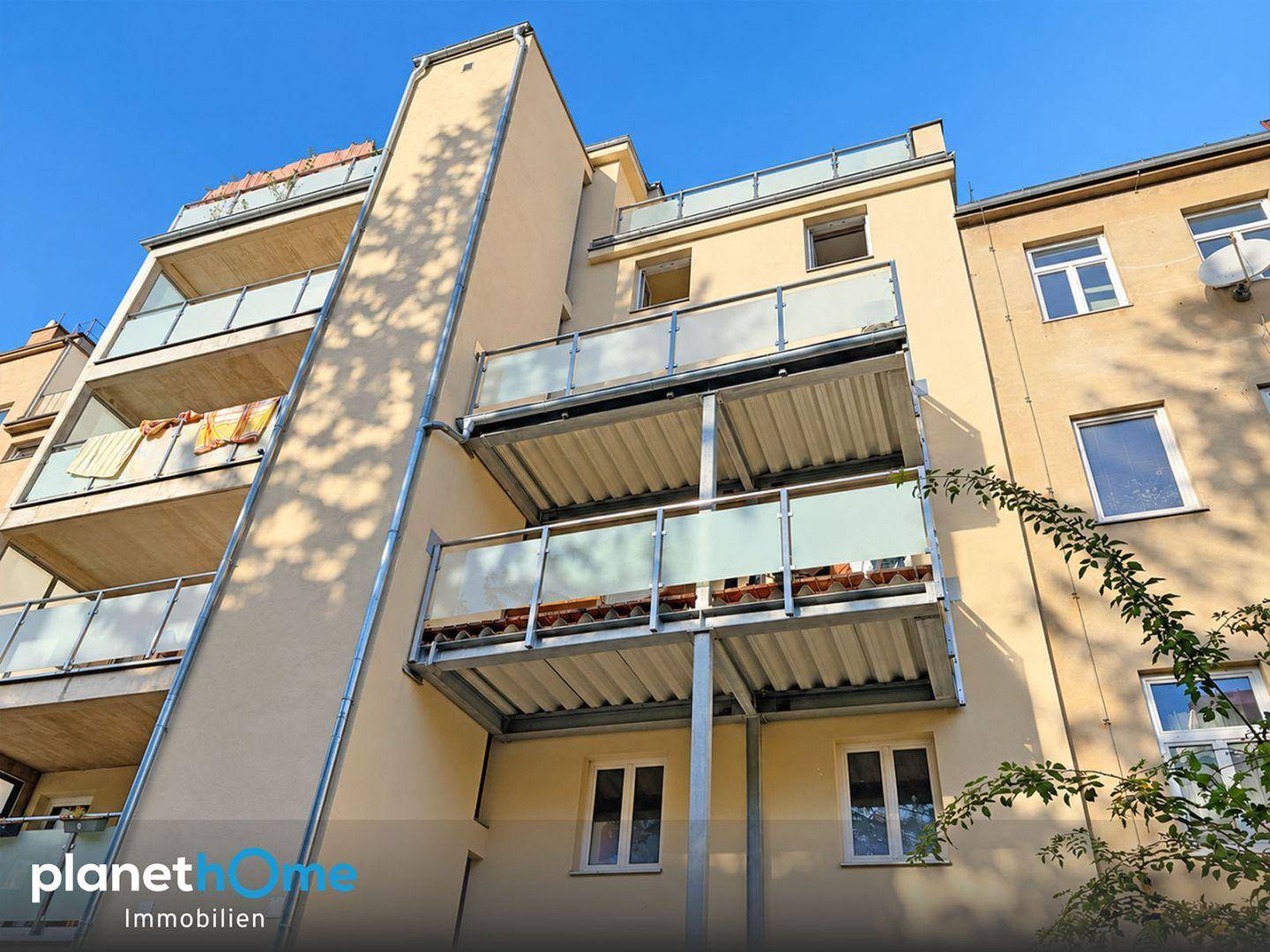 Fassade eines Mehrfamilienhauses mit mehreren Balkonen und Glasgeländern.