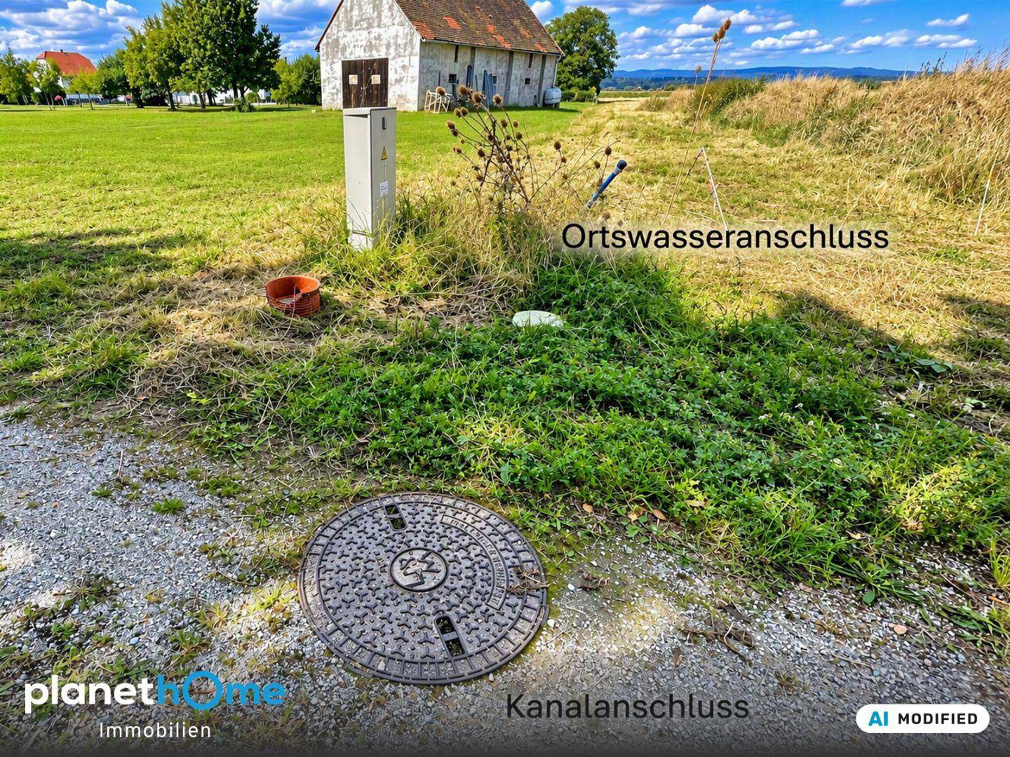 Kanalanschluss und Ortswasseranschluss auf dem Grundstück mit einem Stromkasten und Gebäuden im Hintergrund.