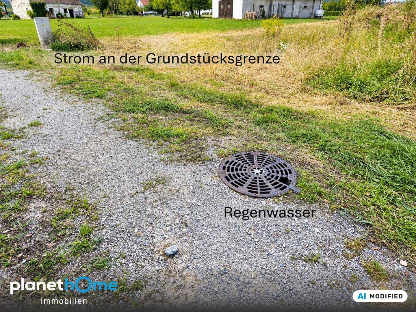 Kiesweg mit Regenwasserabfluss und Stromanschluss an der Grundstücksgrenze, Gebäude im Hintergrund.