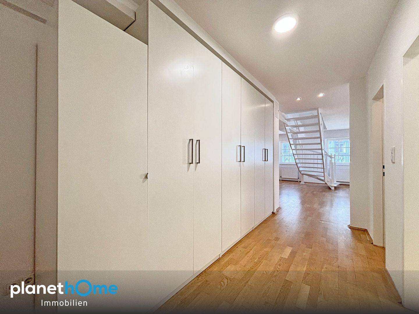 Geräumiger Flur mit praktischen Einbauschränken und Blick auf die Treppe zum Wohnbereich.