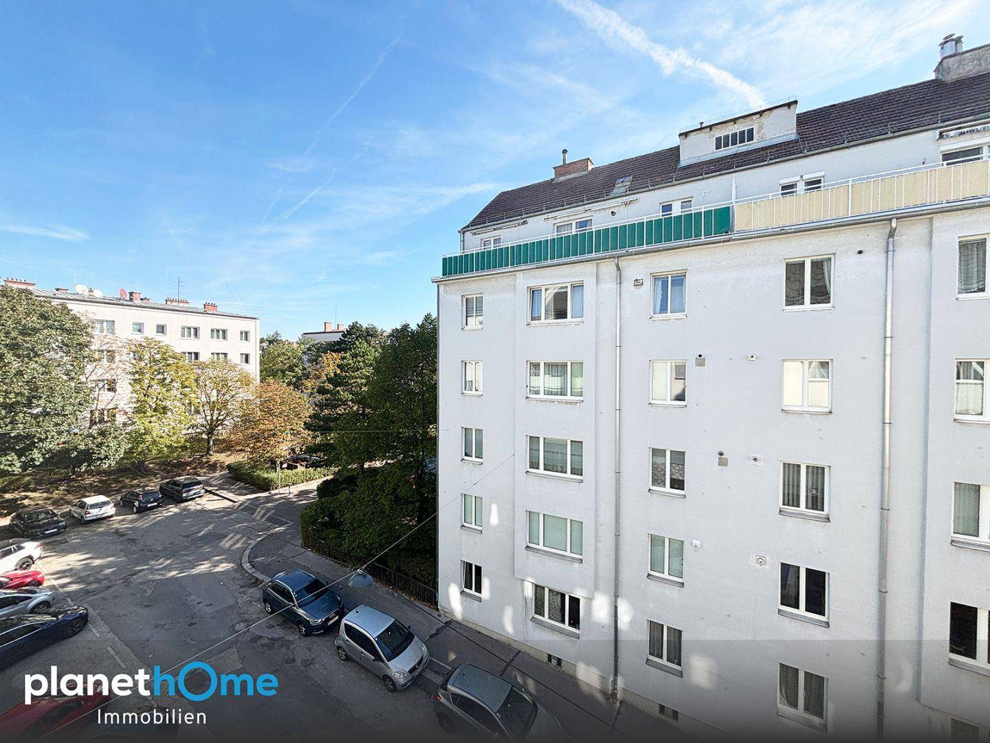 Mehrfamilienhaus mit Blick auf die Straße und umliegende Gebäude unter blauem Himmel.