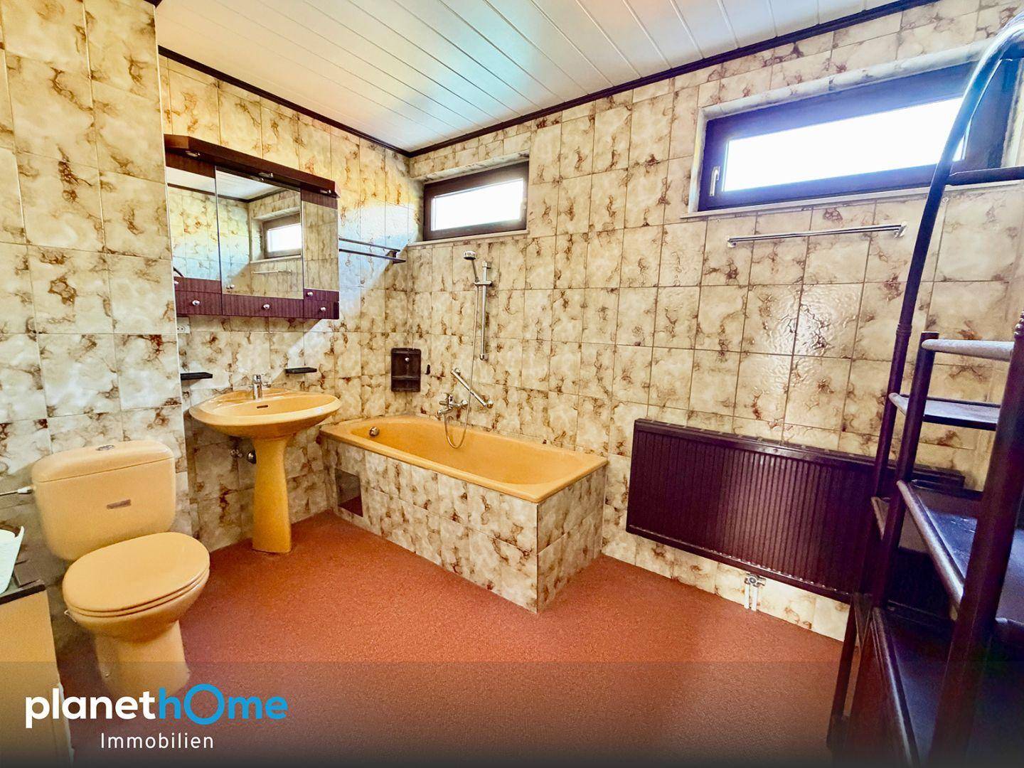 Badezimmer im Stil der 80er Jahre mit orangefarbenen Fliesen, Badewanne und Fenster.