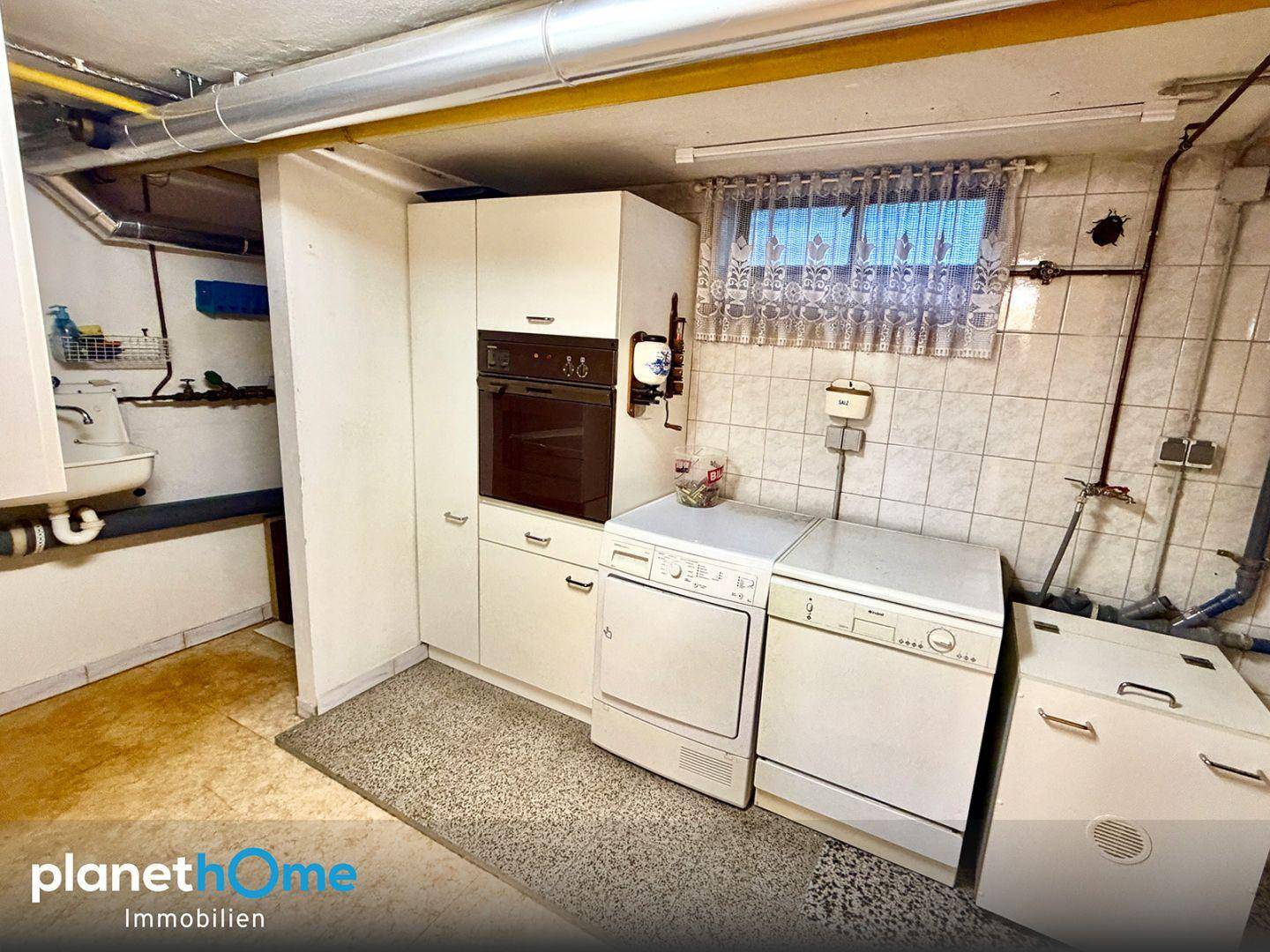 Waschküche im Keller mit Waschmaschine, Trockner und praktischen Einbauschränken.