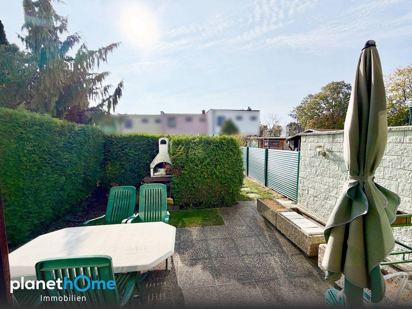 Gemütliche Terrasse mit Gartenmöbeln, Grillplatz und hoher Hecke für Privatsphäre.