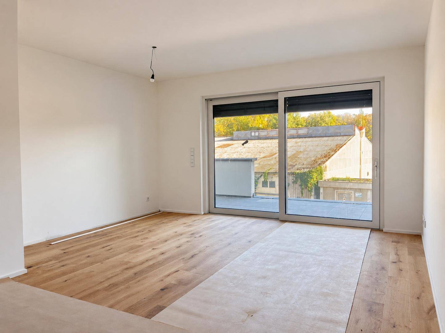 Heller Wohnraum mit Holzboden und großer Schiebetür zum Außenbereich.