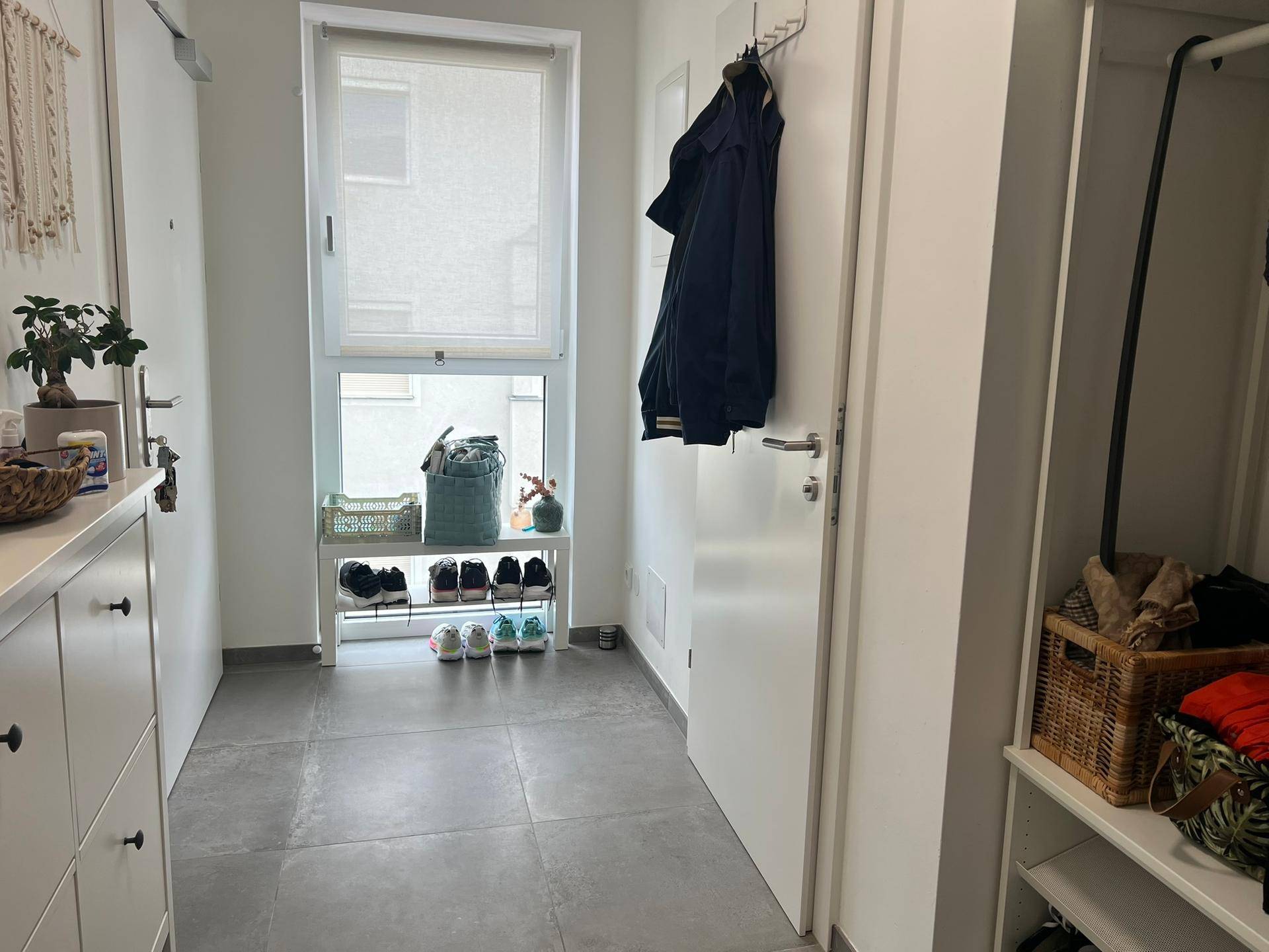 Heller Eingangsbereich mit Fliesenboden, Schuhregal und Garderobe, funktional eingerichtet.