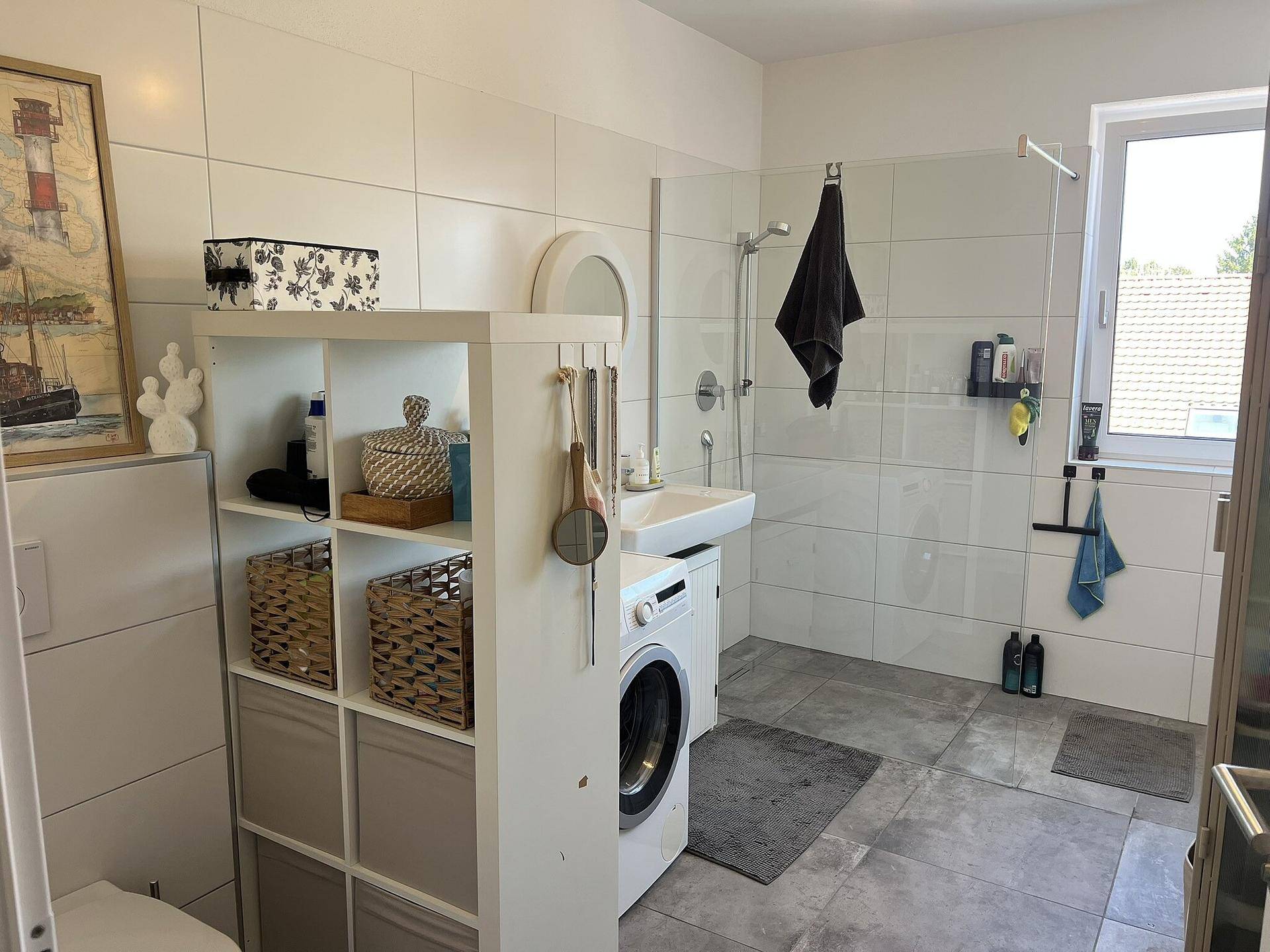 Modernes Badezimmer mit begehbarer Dusche, Waschmaschine und Fenster.