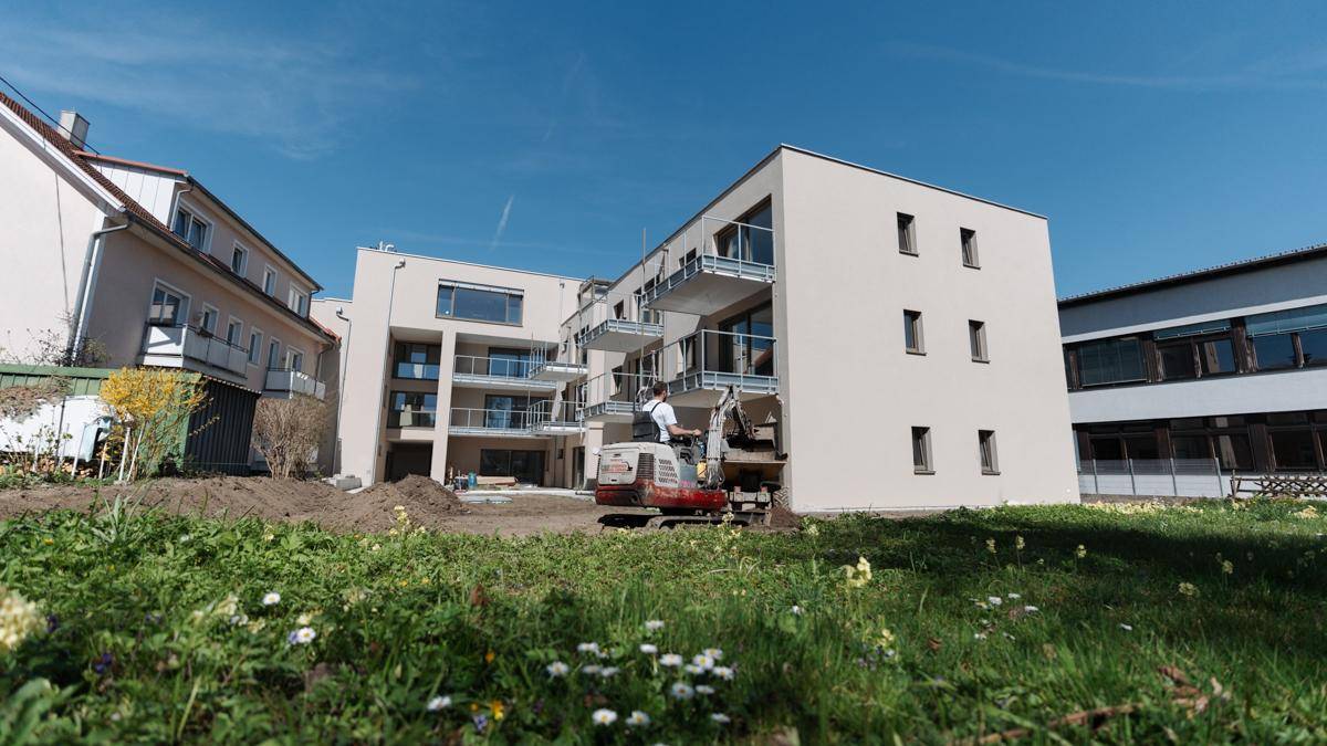 Neubau eines modernen Wohngebäudes mit Balkonen und großen Fenstern, umgeben von Grünflächen.