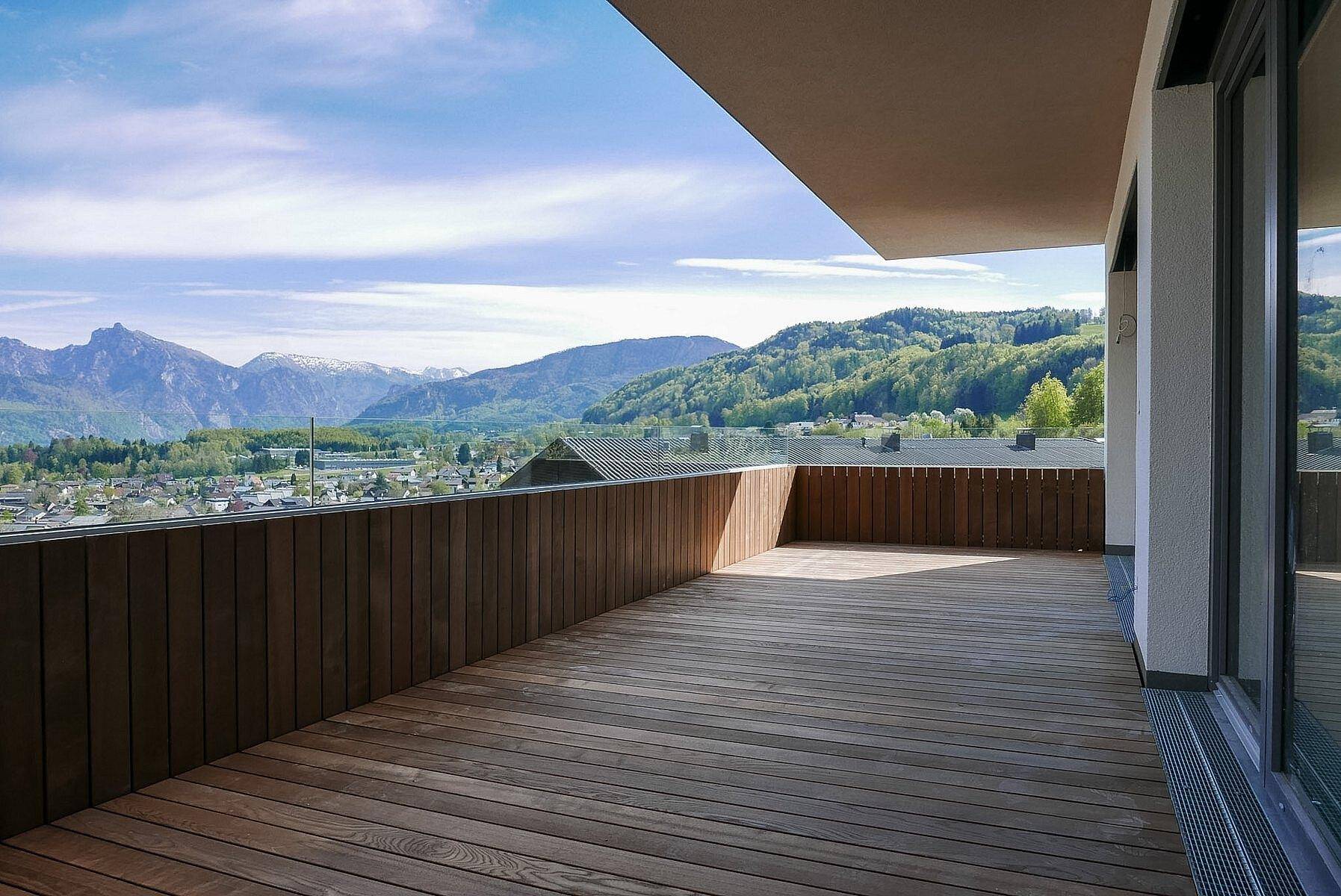 Großzügige Terrasse mit Holzdielen und weitem Blick über die Landschaft und die Berge.