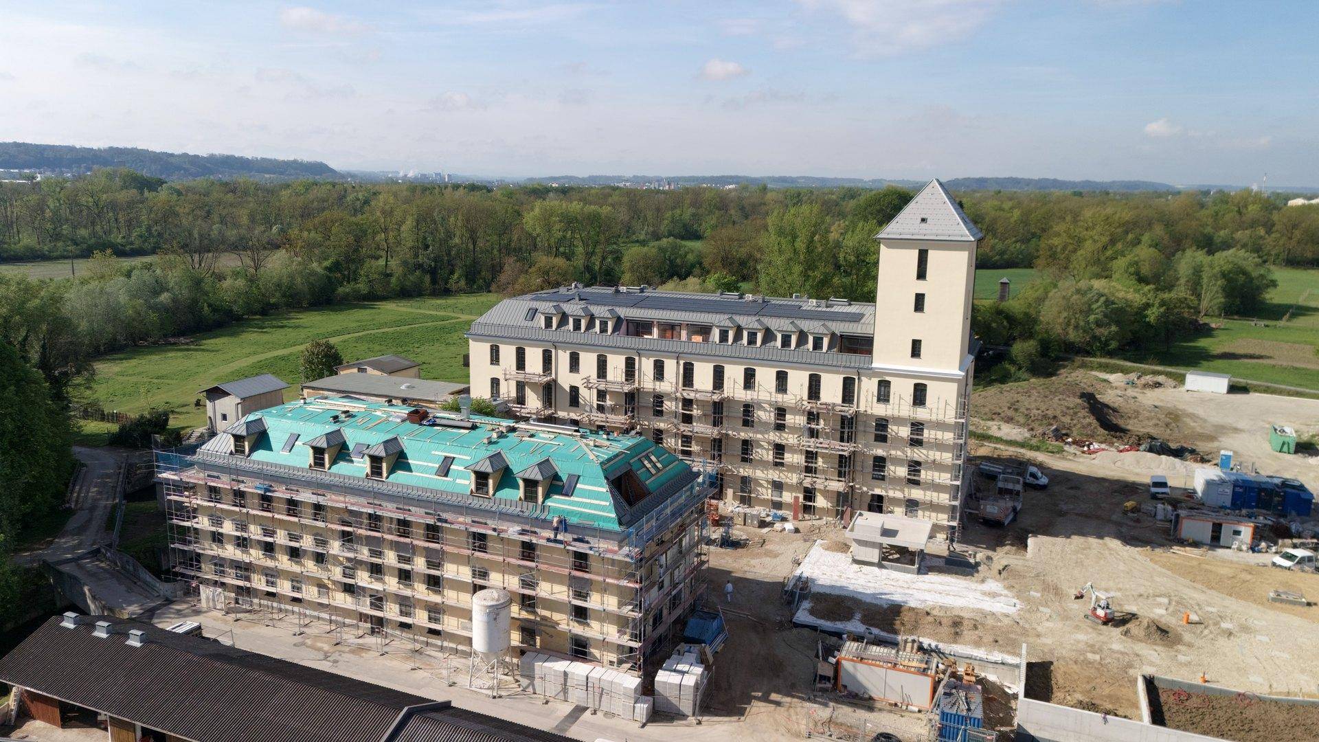Luftaufnahme einer Baustelle mit zwei Gebäuden im Bau und ländlicher Umgebung.