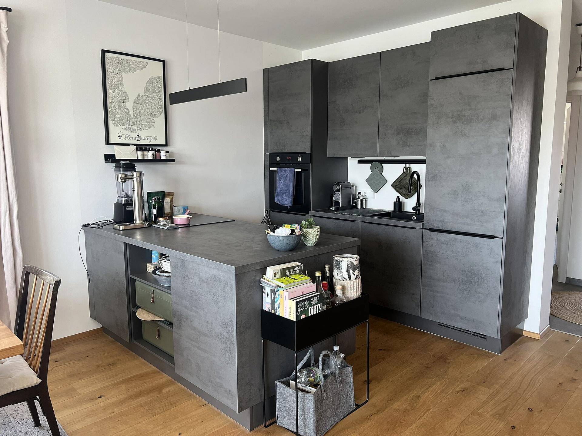 Moderne Küche mit grauen Schränken, Kücheninsel und integrierten Geräten.
