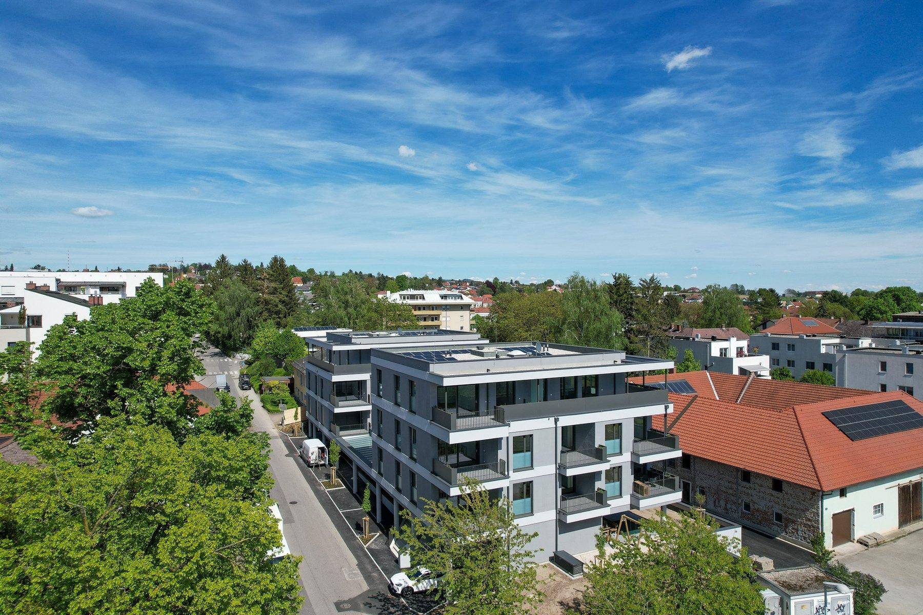 Luftaufnahme des modernen Wohngebäudes in grüner Umgebung mit Weitblick, architektonisch ansprechend.