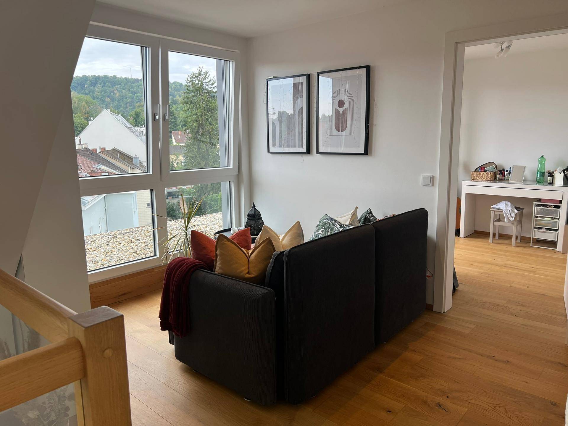 Gemütlicher Wohnbereich im Obergeschoss mit Sofa und großer Fensterfront, bietet Weitblick.