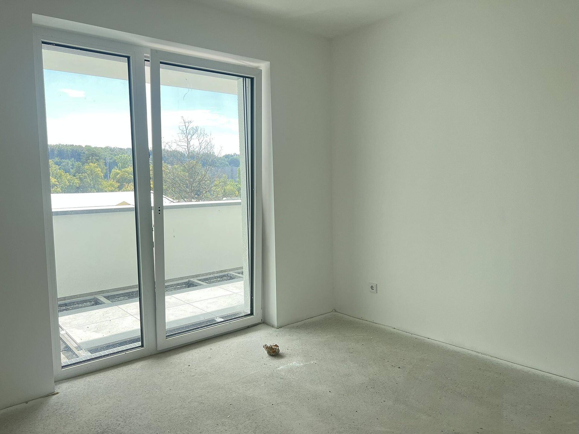 Unmöblierter Raum mit Schiebetür zum Balkon, bietet viel Tageslicht und eine offene Atmosphäre.