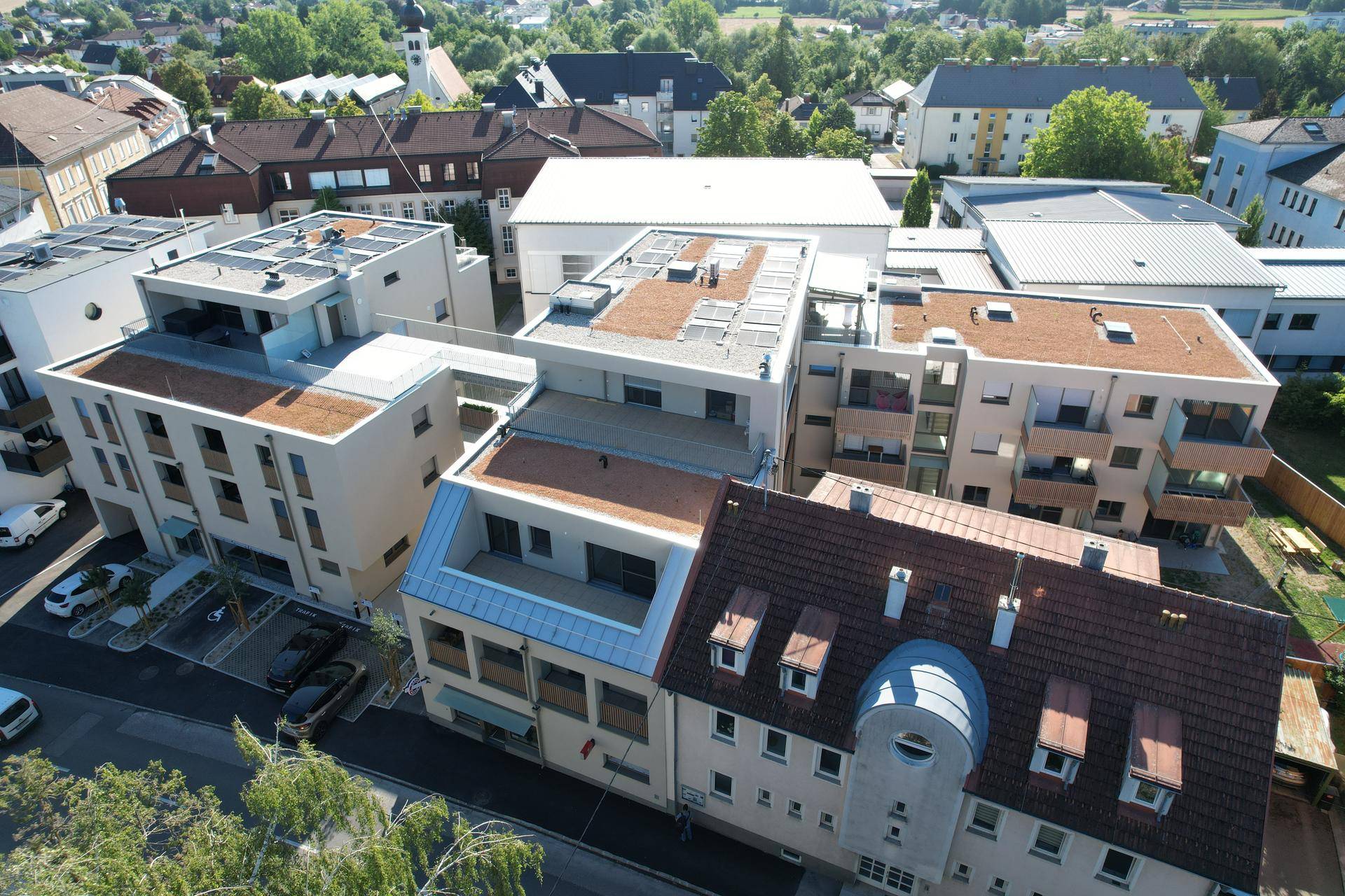 Vogelperspektive auf einen modernen Wohnkomplex mit begrünten Flachdächern und Solarpaneelen in einer Siedlung.