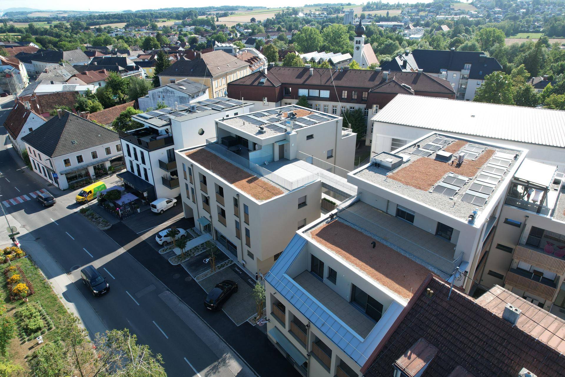 Weitläufige Luftaufnahme eines neuen Wohngebäudes mit Solaranlagen auf den Dächern und umliegender Bebauung.