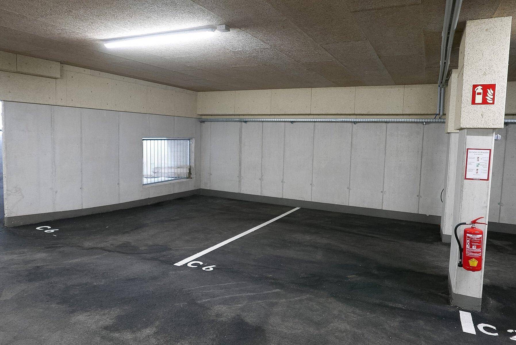 Geräumige Tiefgarage mit markierten Stellplätzen und Brandschutzvorrichtungen.