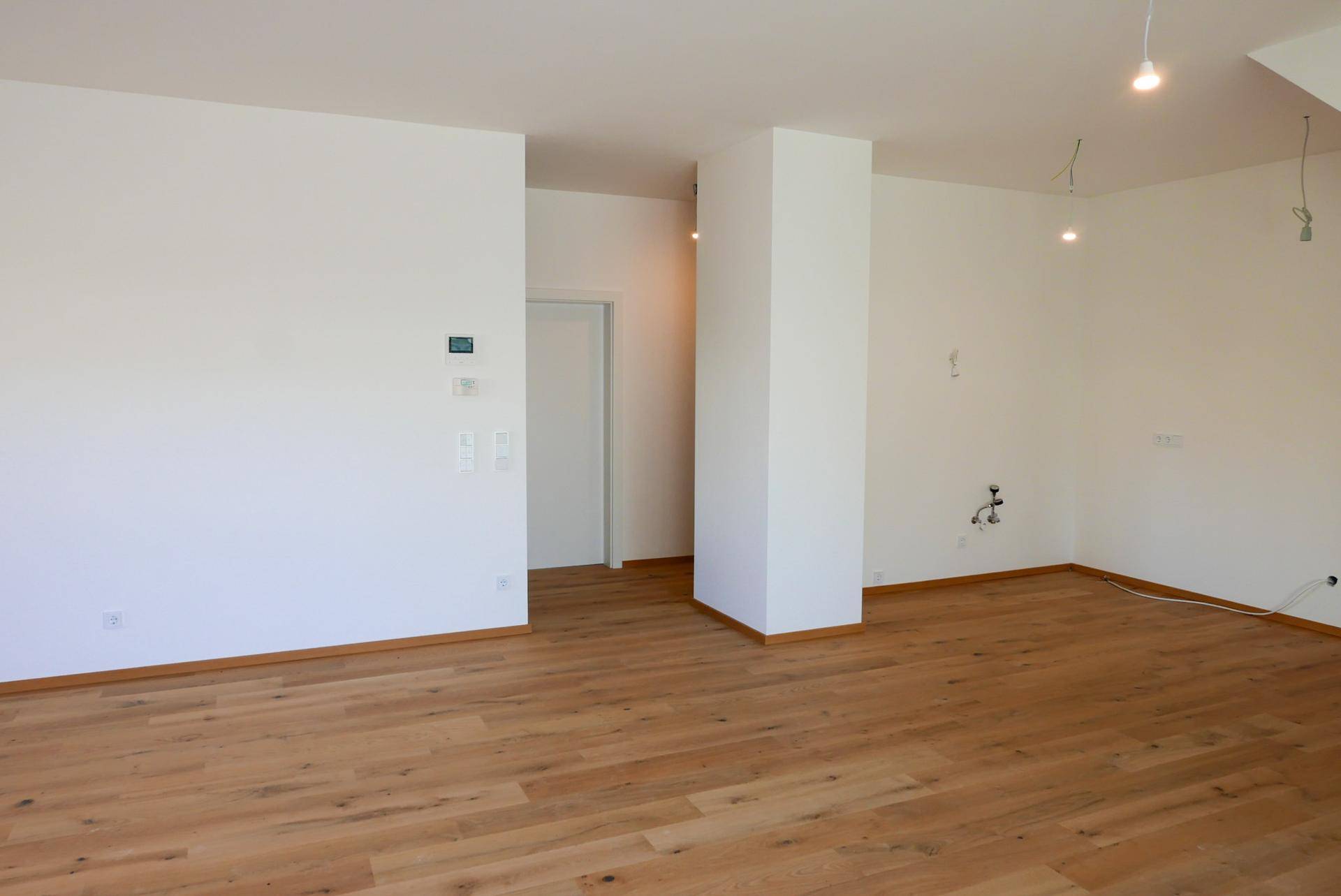 Leerer Raum mit hellem Holzboden und weiß gestrichenen Wänden, ideal für Wohn- oder Essbereich.