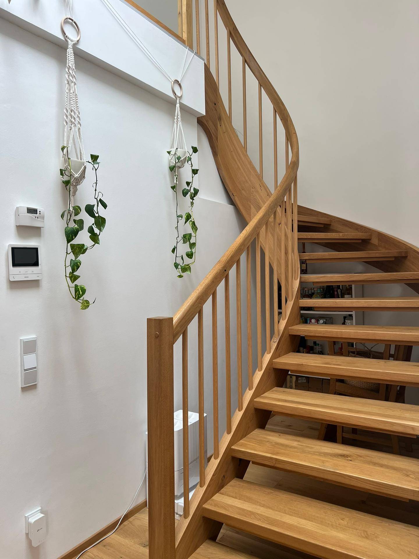 Elegante Holztreppe mit geschwungenem Geländer, die verschiedene Ebenen verbindet.