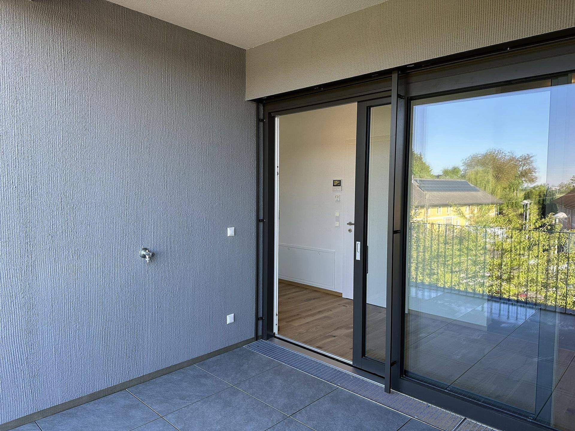 Geräumiger Balkon mit Fliesenboden und Blick auf die grüne Umgebung, ideal zum Entspannen.