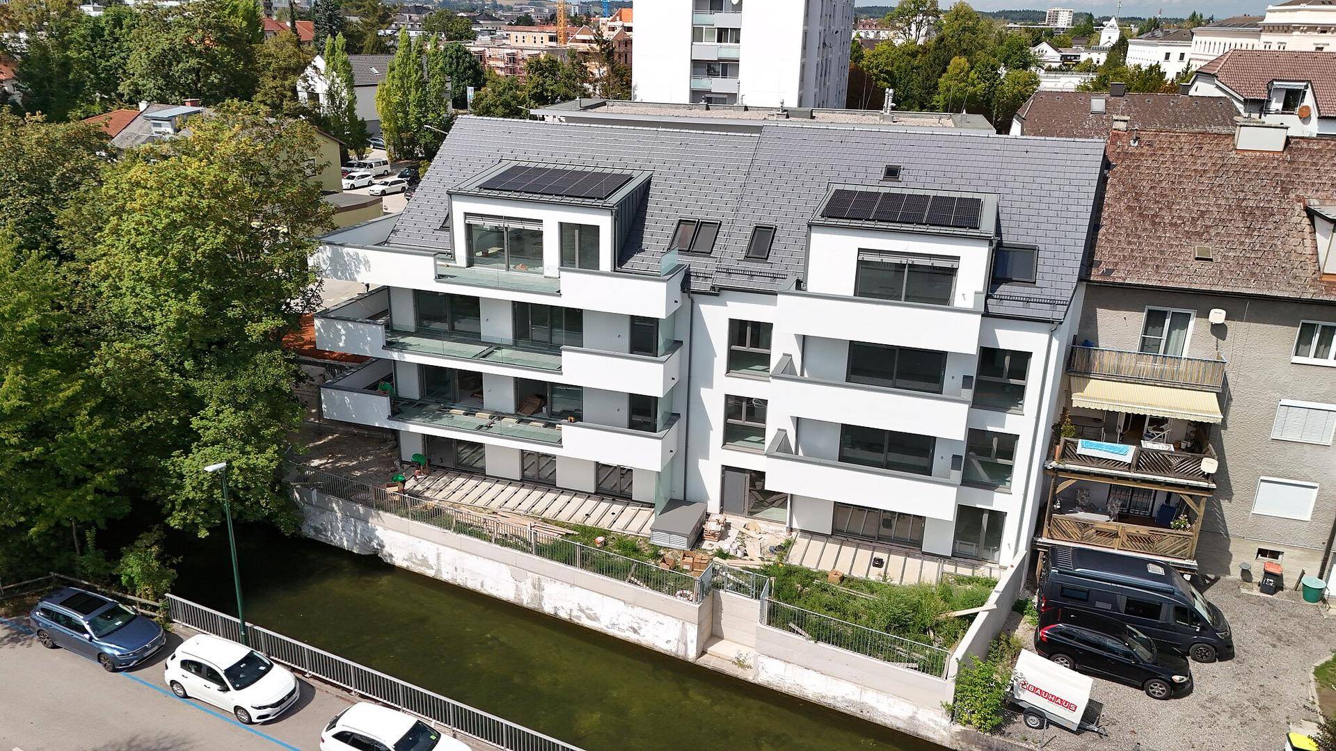 Neubau mit moderner Architektur, weißen Balkonen und Blick auf das Wasser.