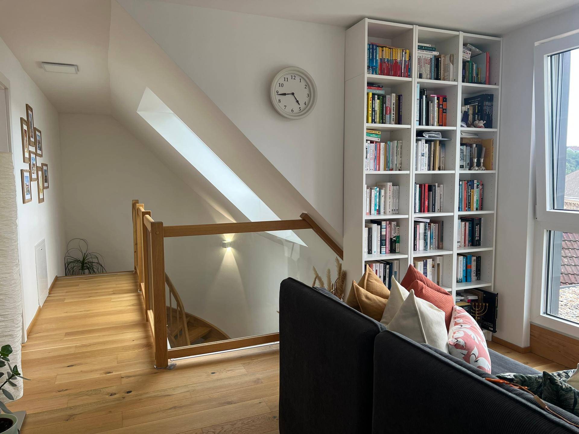 Offener Wohnbereich im Obergeschoss mit Bücherregal und Blick auf die Treppe.