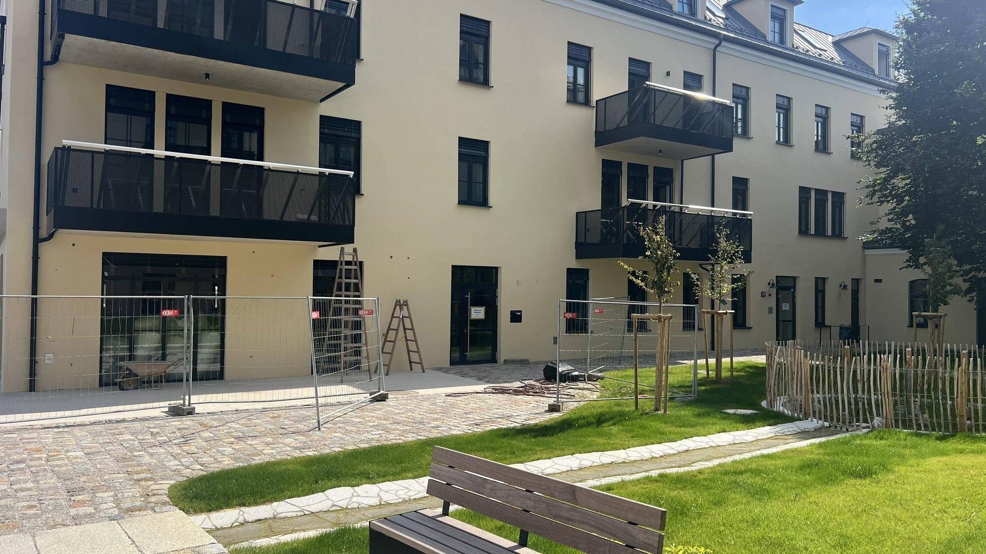 Neubau-Wohngebäude mit Balkonen, heller Fassade und einem gepflegten Rasenbereich im Vordergrund.