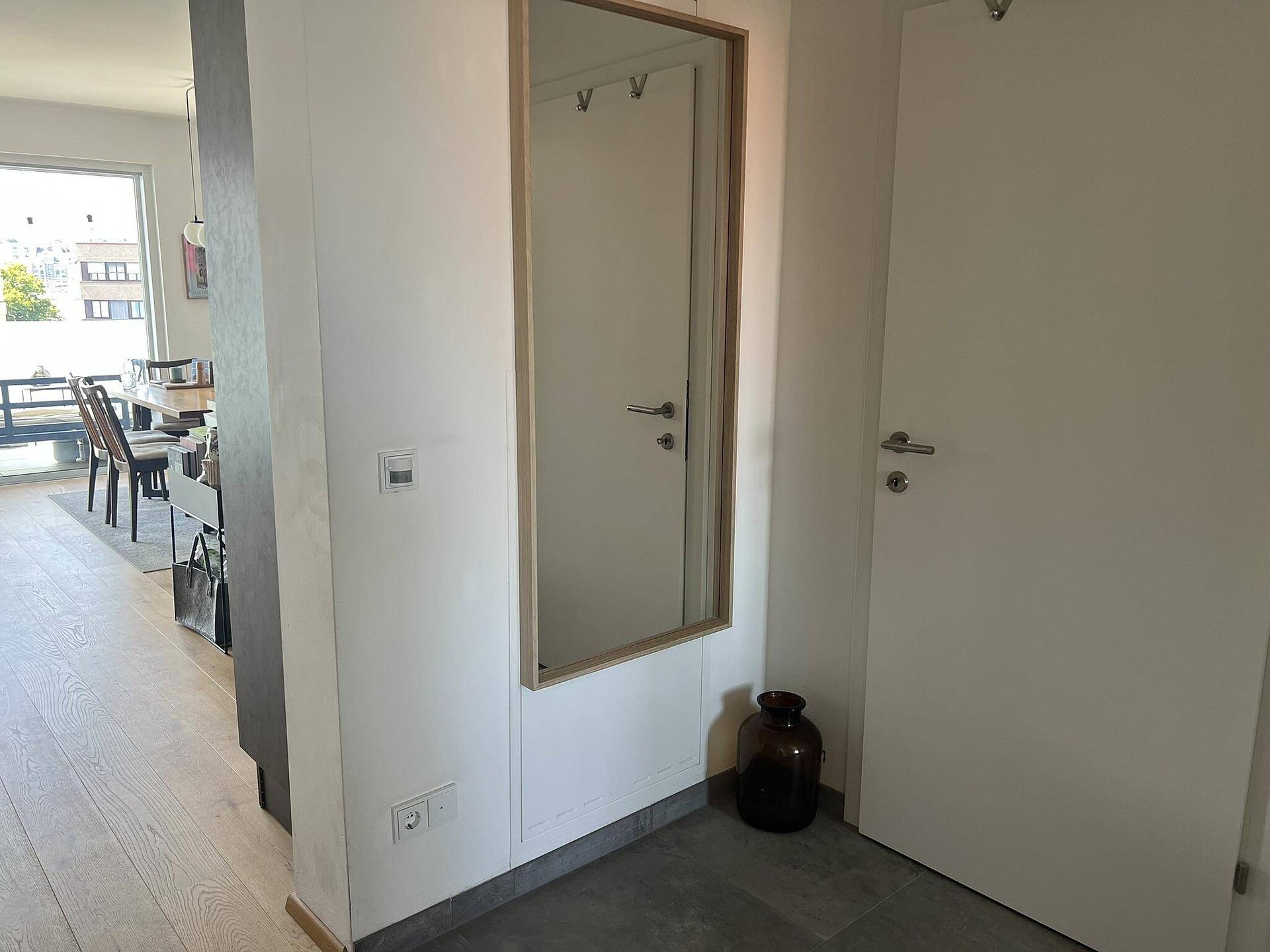 Heller Eingangsbereich mit großem Spiegel und Blick in den Wohnbereich.