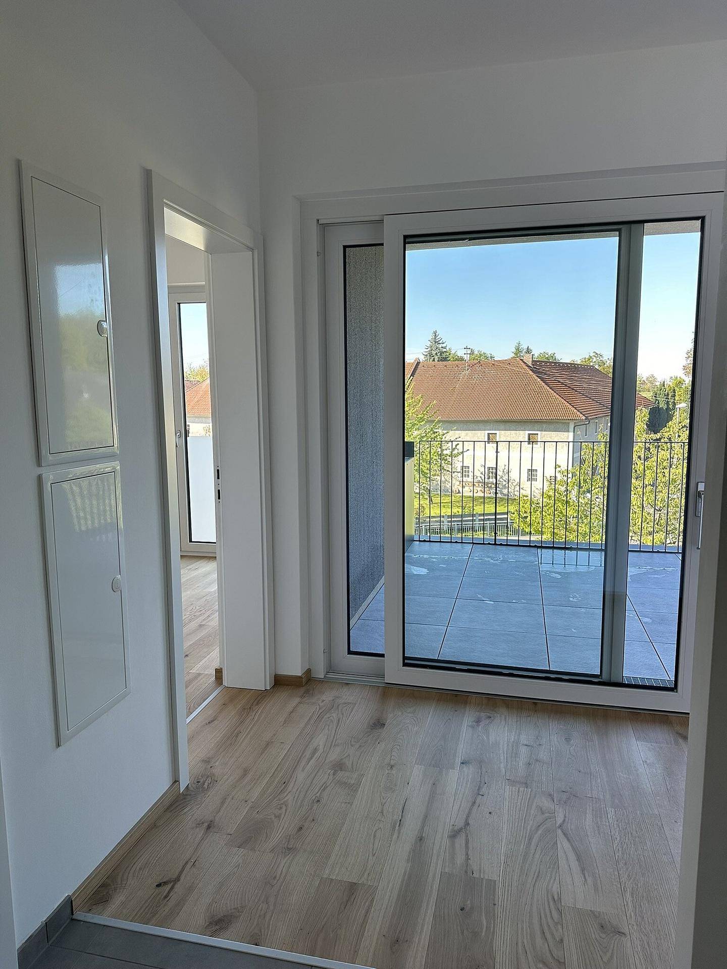 Heller Flur mit Holzboden und direktem Zugang zum Balkon, bietet einen schönen Ausblick.