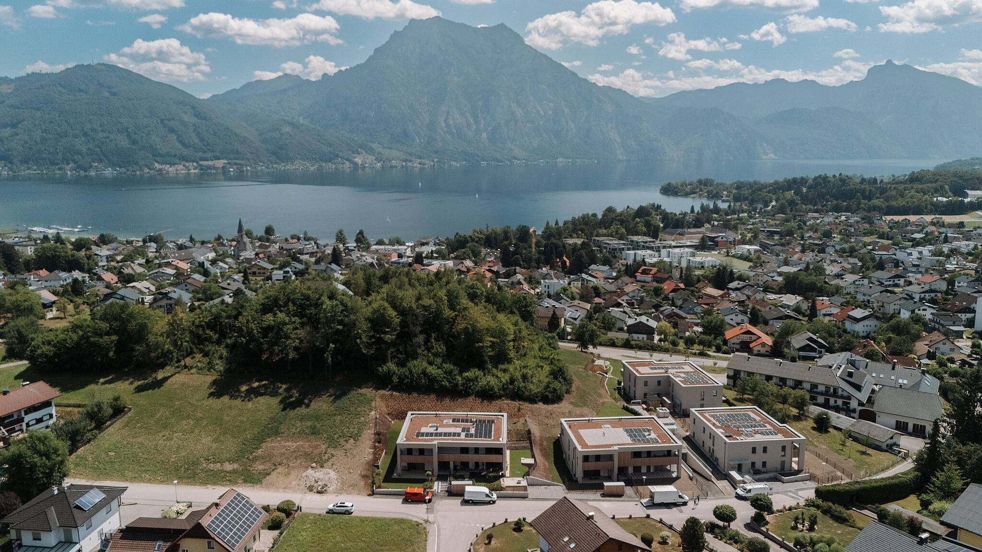 Luftaufnahme der Neubauten in einer malerischen Umgebung mit See- und Bergblick.