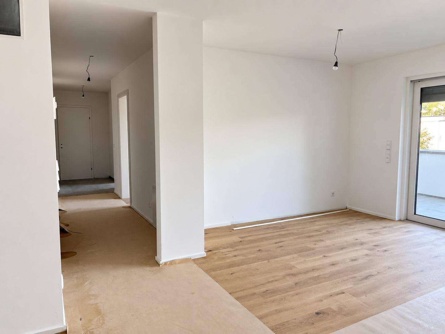 Geräumiger, heller Wohnbereich mit Holzboden und offenem Übergang zum Flur.