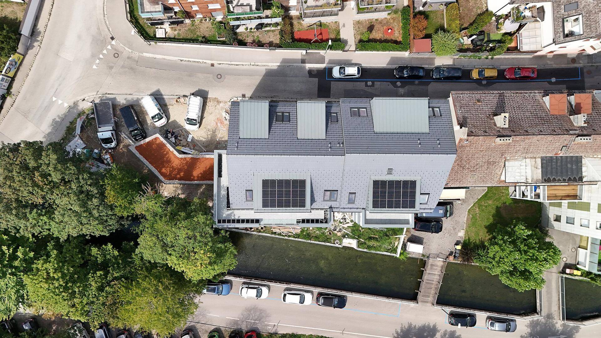 Luftaufnahme des Neubaus mit Solaranlagen auf dem Dach und angrenzendem Kanal.