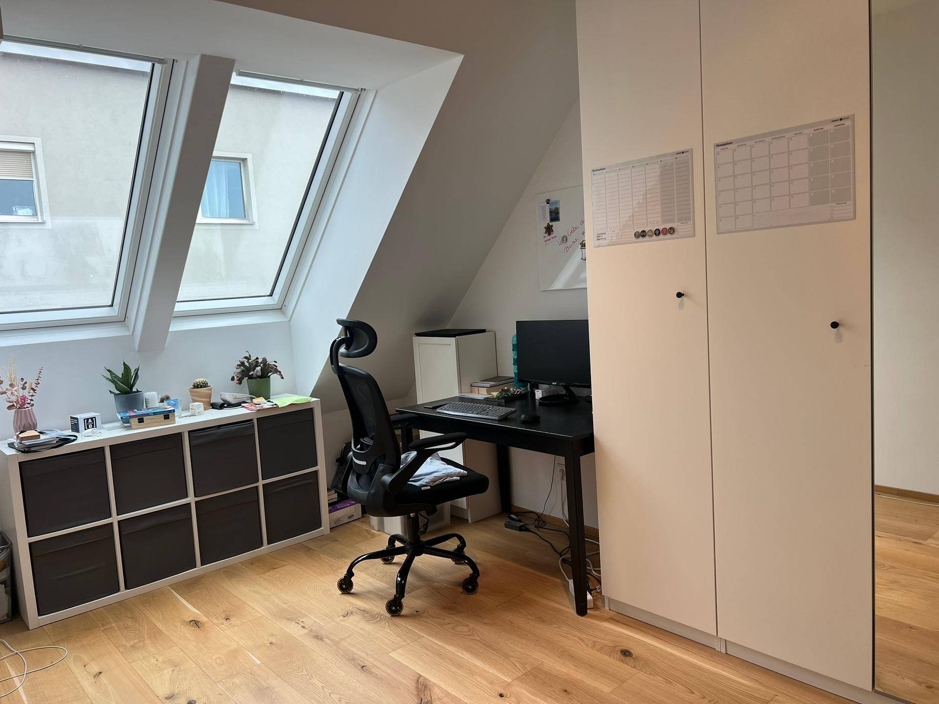 Helles Arbeitszimmer im Dachgeschoss mit Schreibtisch, Schränken und großen Dachfenstern.