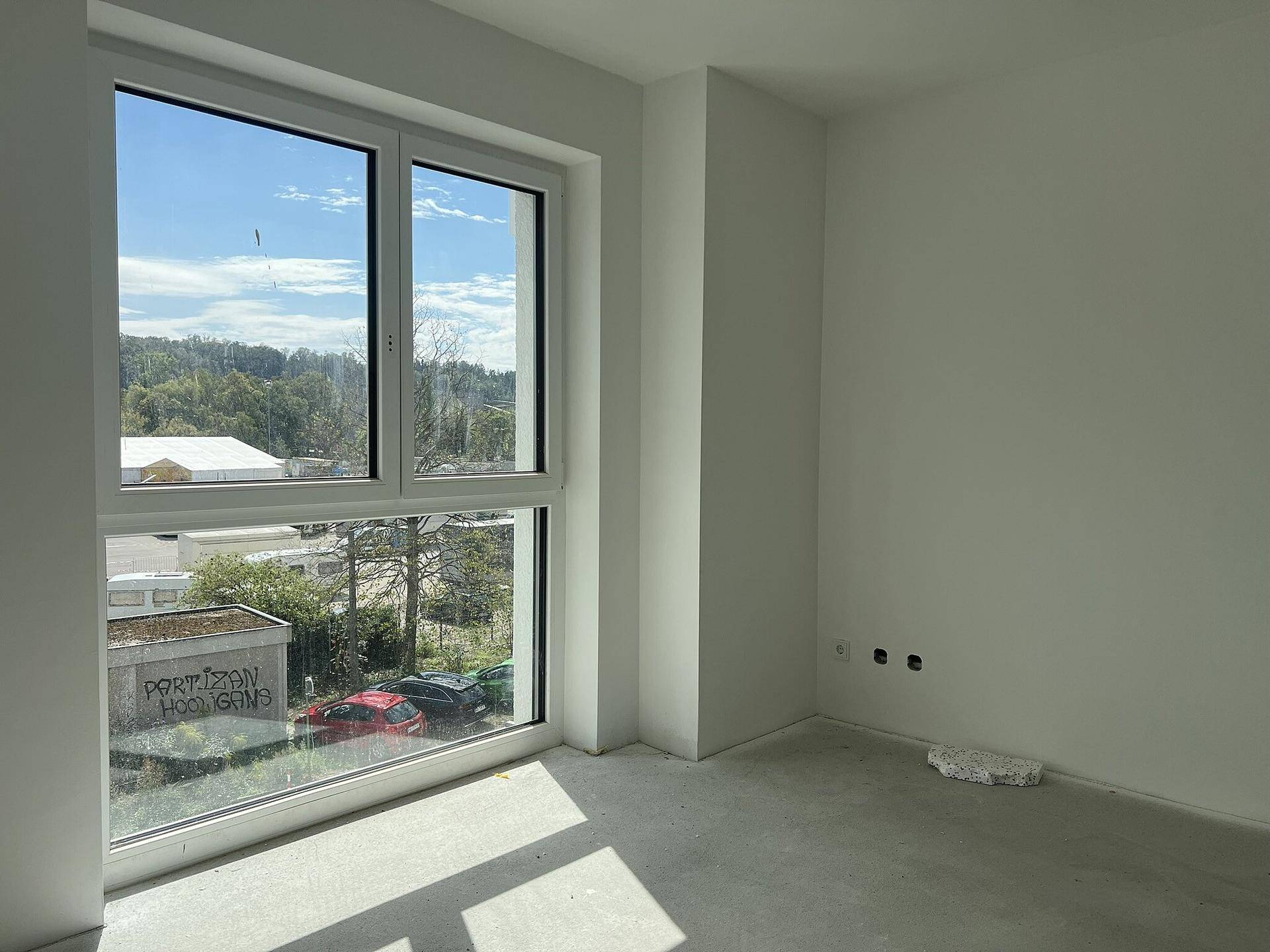 Unmöblierter Raum mit großen Fenstern, die viel Tageslicht hereinlassen und eine weite Aussicht bieten.