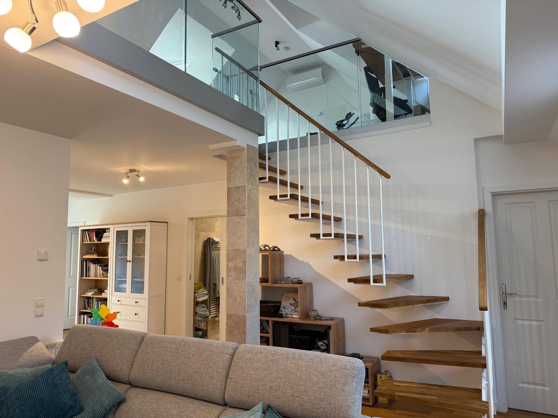 Geräumiger Wohnbereich mit moderner Holztreppe, Glasgeländer und offener Galerie.