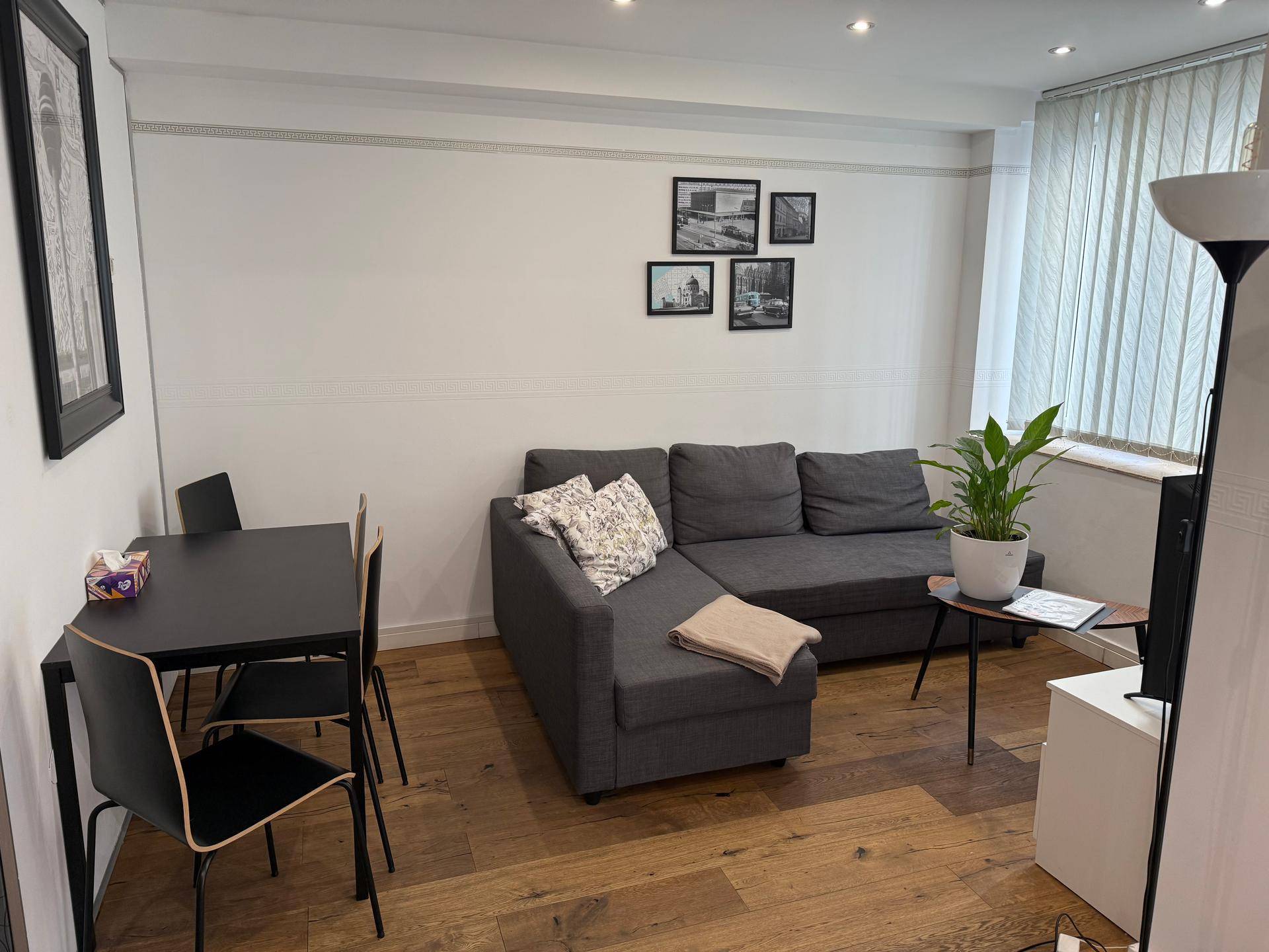 Kombinierter Wohn- und Essbereich mit grauem Sofa, Esstisch und Holzboden.