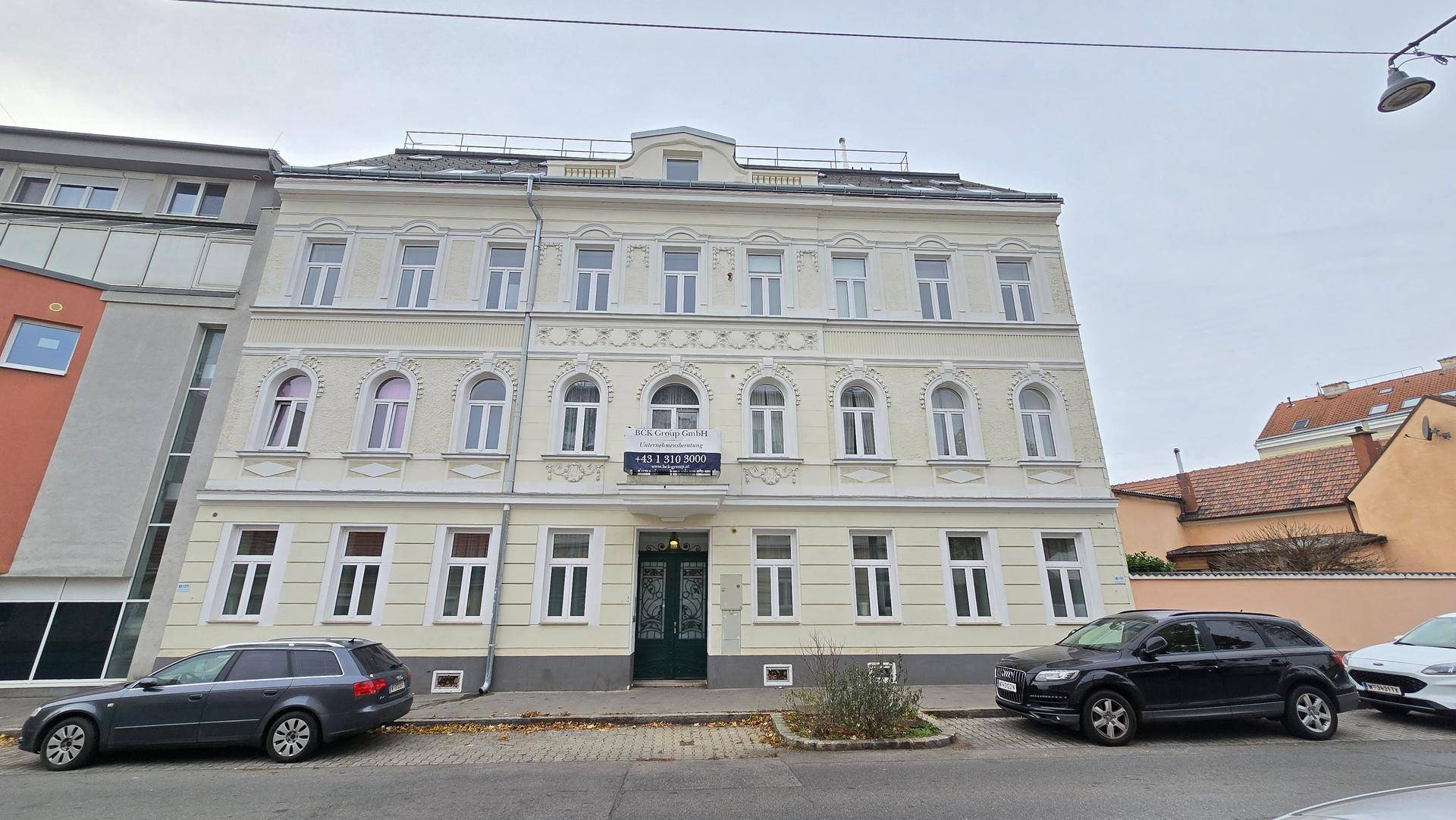 Klassische Fassade eines Mehrfamilienhauses mit vielen Fenstern und traditionellen Details.