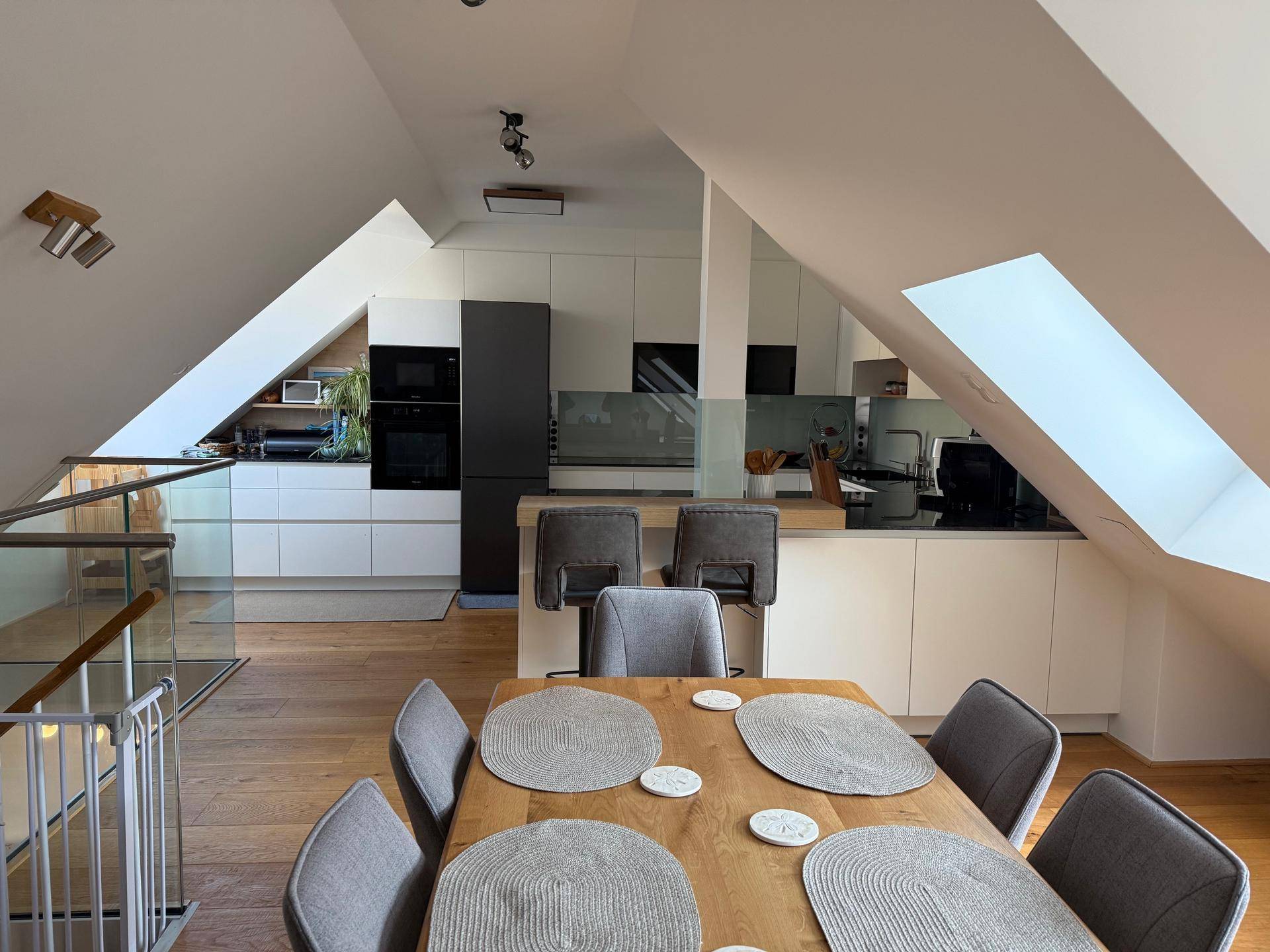 Moderne offene Küche mit Essbereich, Dachschrägen und viel natürlichem Licht.