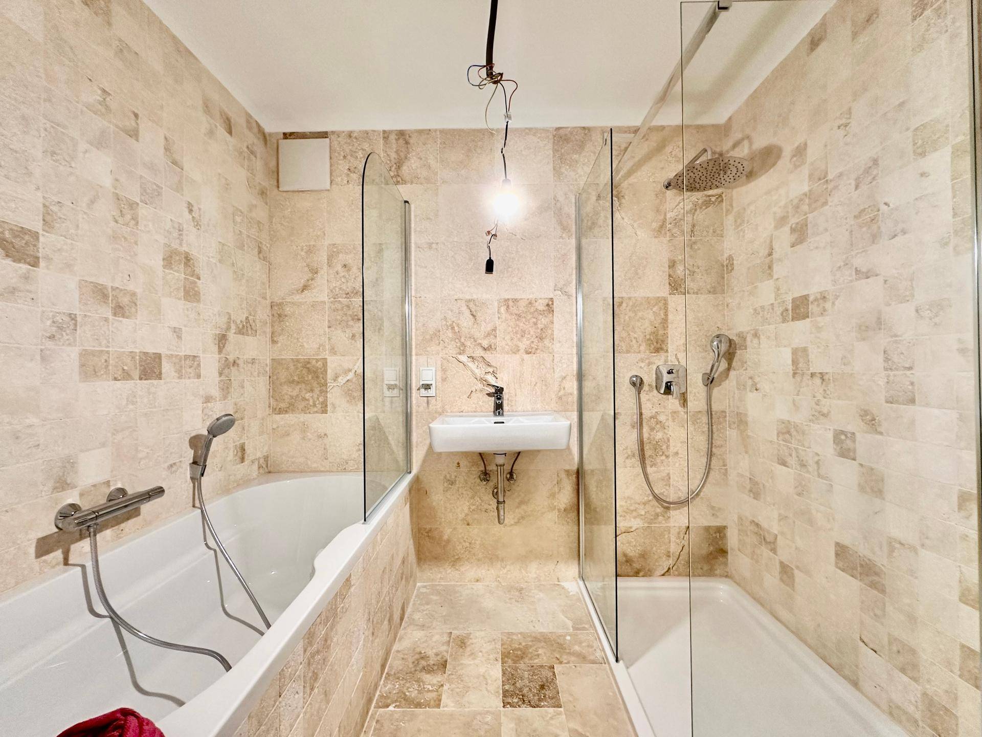 Geräumiges Badezimmer mit Badewanne, Duschkabine und beigefarbenen Fliesen.