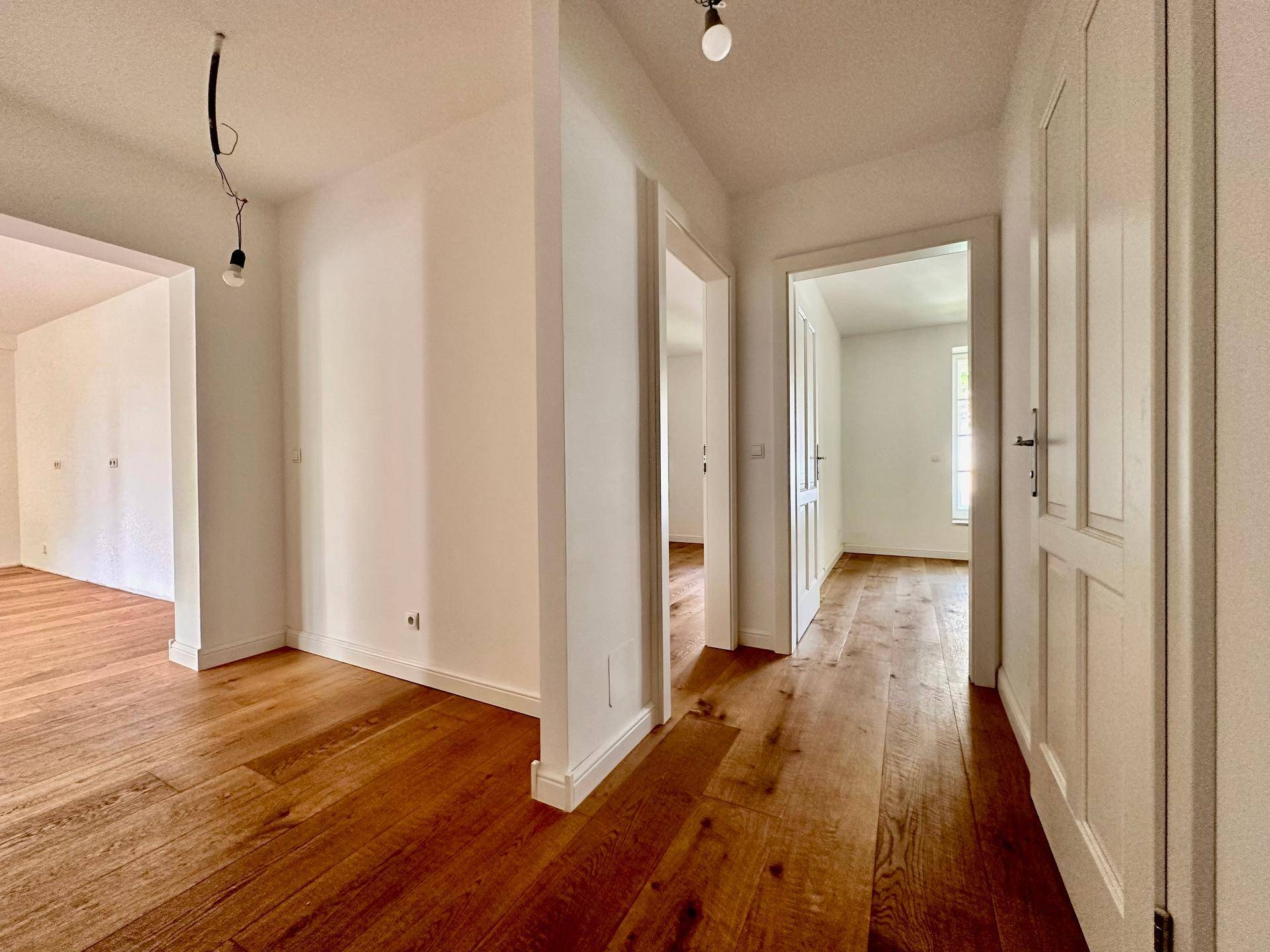 Heller Flur mit Holzboden und mehreren Türen, die zu verschiedenen Räumen führen.