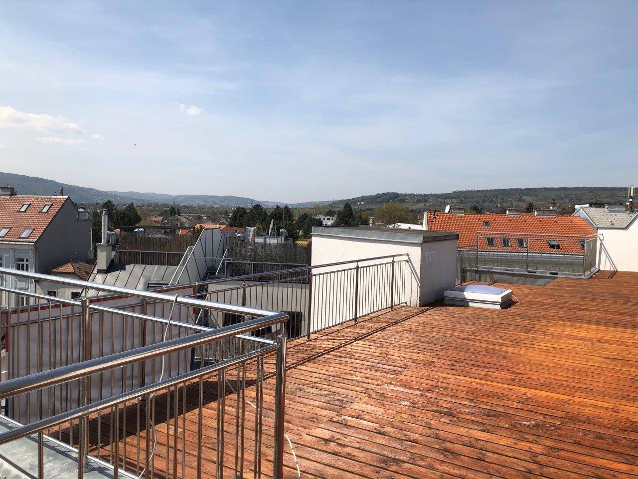 Große Dachterrasse mit Holzboden und weitem Blick über die Stadt und die umliegende Landschaft.