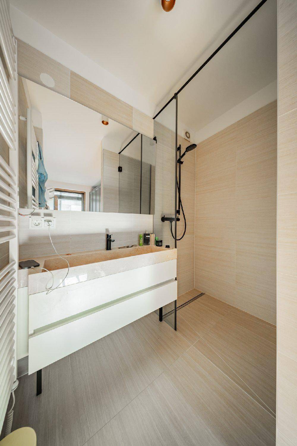 Modernes Badezimmer mit ebenerdiger Dusche, Einzelwaschbecken und beheiztem Handtuchhalter.