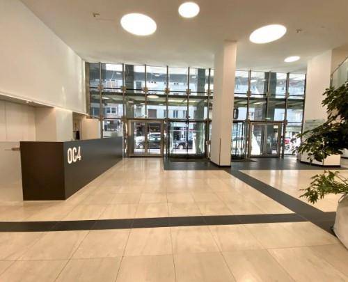 Helle und moderne Lobby mit großformatigen Fliesen, einer Rezeption und großen Fenstern, die viel Tageslicht hereinlassen.