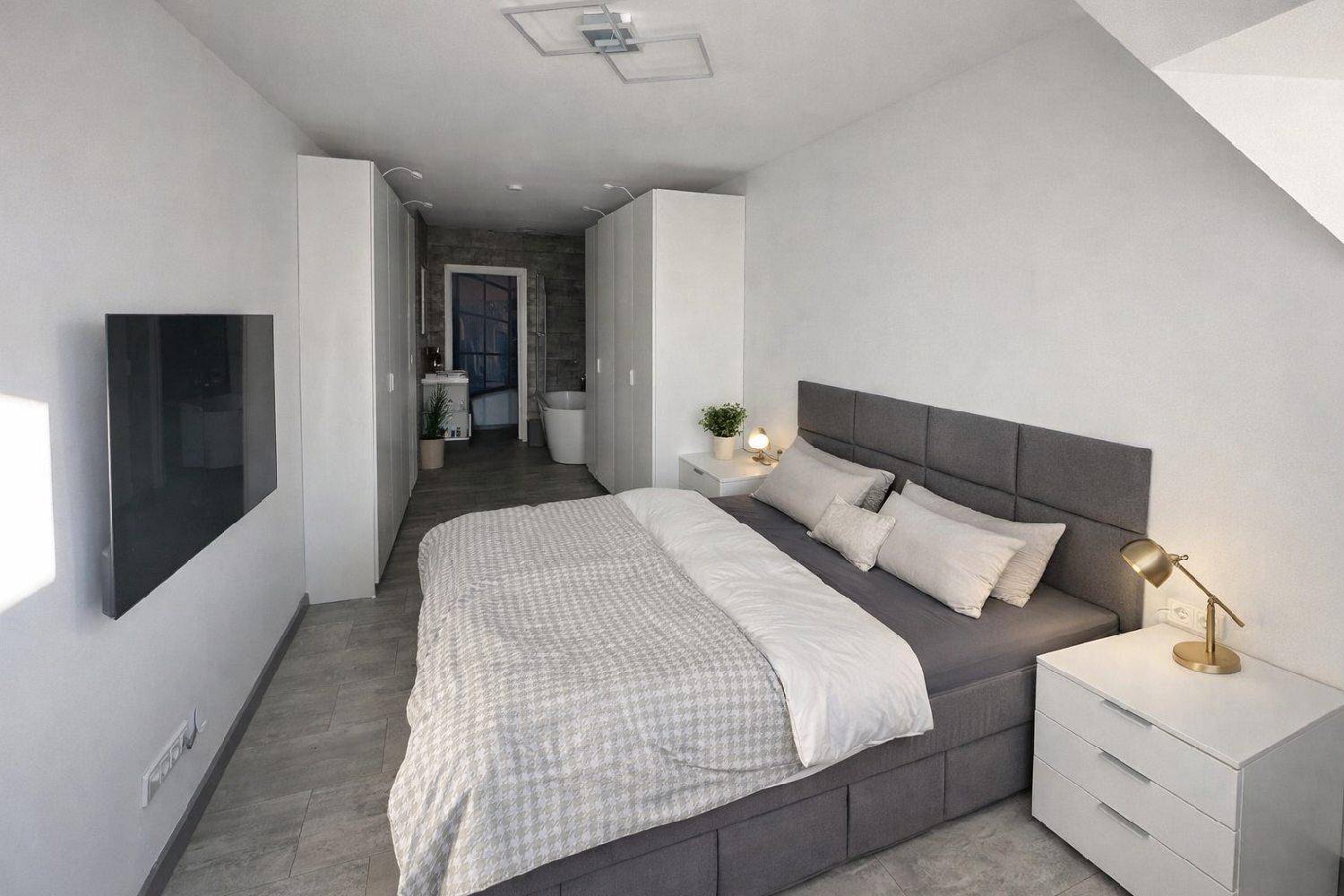 Modernes Schlafzimmer mit Doppelbett, Einbauschränken und direktem Zugang zum Badezimmer.