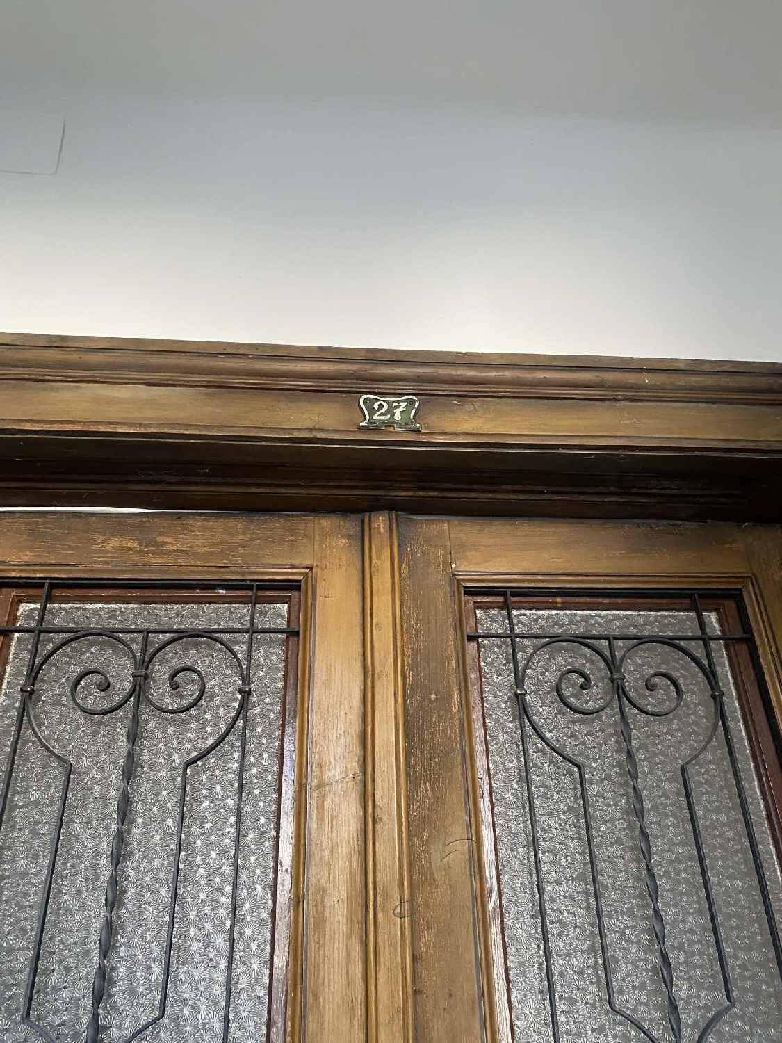 Historische Holztür mit dekorativen Metallgittern und der Wohnungsnummer 27 in einem Altbau.