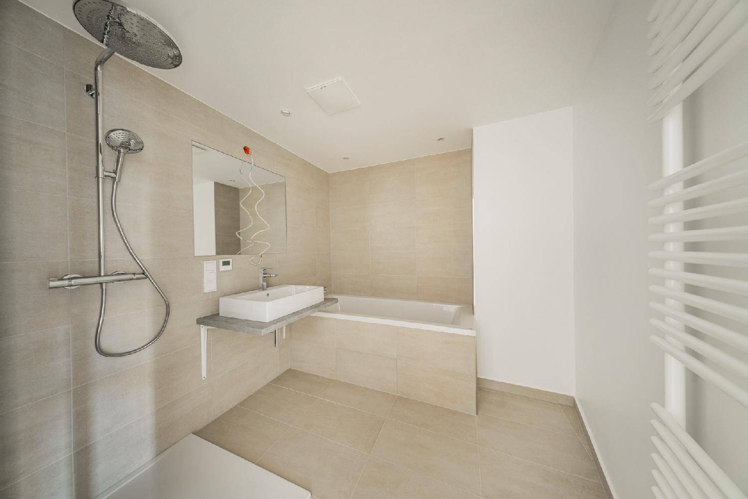 Modernes Badezimmer mit Badewanne, Dusche und beheiztem Handtuchhalter in hellen Farbtönen.