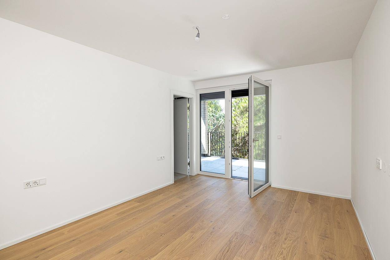 Leeres Zimmer mit Holzboden und Zugang zu einem Außenbereich, ideal als Schlaf- oder Arbeitszimmer.