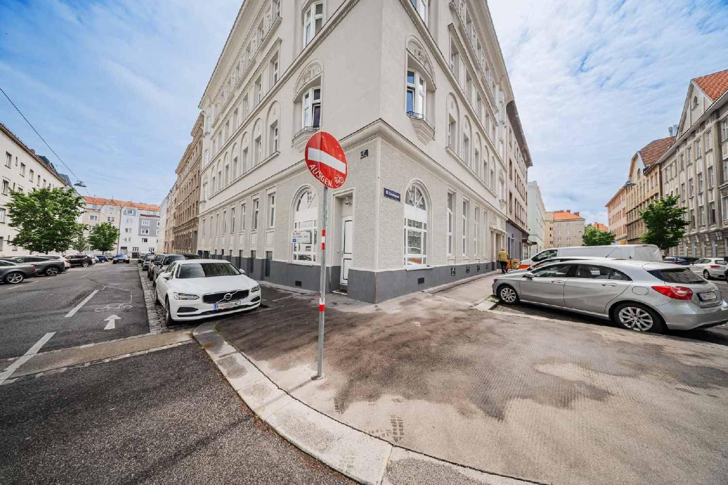 Historisches Eckgebäude mit klassischer Architektur und vielen Fenstern an einer belebten Straße.